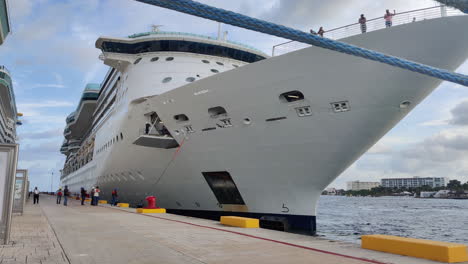 Amid-the-pier's-hustle,-determined-group-of-individuals-pulls-hefty-mooring-line,-securing-massive-cruise-ship-with-teamwork-and-precision-|-Group-of-people-pulling-heavy-mooring-line-of-Ship