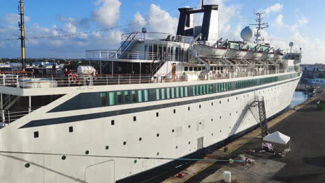 Capture-the-allure-of-the-Caribbean:-panning-shot-reveals-small-private-cruise-ship,-elegantly-docked-on-the-vibrant-port-of-serene-island