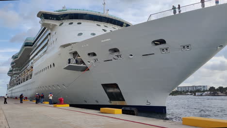 Amid-the-pier's-hustle,-determined-group-of-individuals-pulls-hefty-mooring-line,-securing-massive-cruise-ship-with-teamwork-and-precision-|-Group-of-people-pulling-heavy-mooring-line-of-Ship