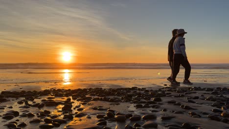 Silhouetten-Von-Menschen,-Die-Während-Eines-Wunderschönen-Sonnenuntergangs-über-Dem-Meer-Von-Rechts-Nach-Links-Gingen