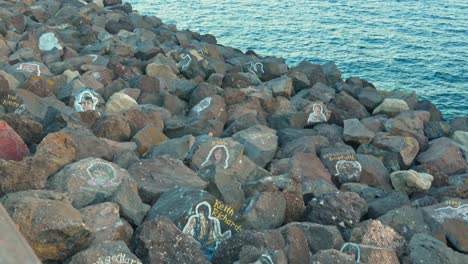 Deich,-Der-Felsen-Trägt,-Die-Mit-Bildumrissen-Und-Namen-Berühmter-Persönlichkeiten-Bemalt-Sind