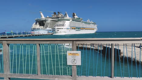 Amidst-the-grandeur-of-docked-cruise-ships,-whimsical-caution-sign-on-the-bridge-adds-touch-of-humor-to-the-bustling-waterfront-scene-|-funny-caution-sign-on-island-with-cruise-ships-docked