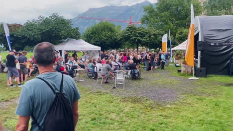 Couple-Holding-Hands-At-Outdoor-Concert-|-Interlaken-Switzerland-Immersive-Travel-Tourism-Mountainside-Valley-Resort-City,-Europe,-Walking,-Rainy-Day,-4K