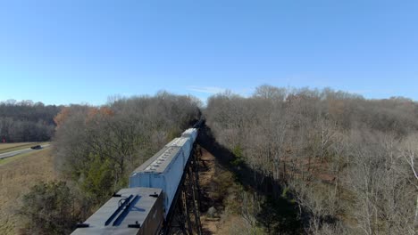 Toma-Aérea-Orbitando-Sobre-Un-Tren-De-Carga-Mixto-Cruzando-El-Caballete-Pope-Lick-En-Louisville,-Kentucky,-En-Un-Soleado-Día-De-Invierno.