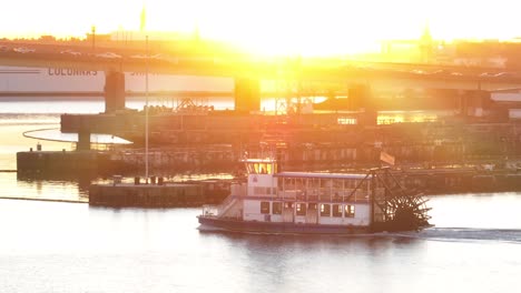 Raddampfer-Auf-Dem-Fluss-Bei-Sonnenaufgang-Mit-Marineschiff-Und-Industriekulisse