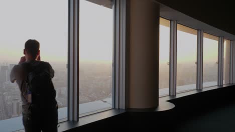 Tourists-overlook-the-skyline-of-Tokyo-while-sunset-from-a-skyscraper-window