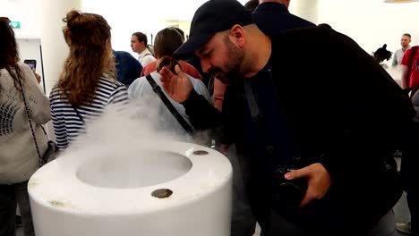 Man-smelling-the-taste-of-barley,-malt,-hops-and-yeast-in-Guinness-Storehouse-white-room