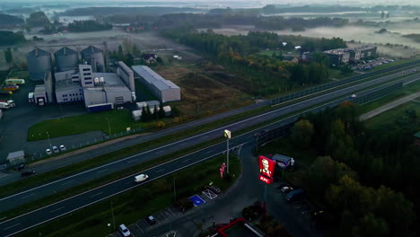 Cars-driving-on-highway-in-morning-haze-in-industrial-city-outskirts