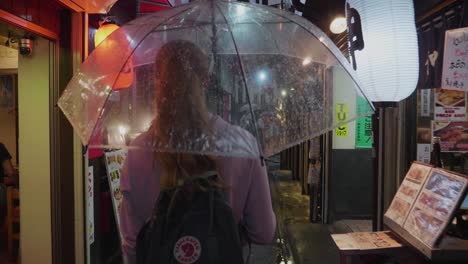 a-single-blonde-european-tourist-is-walking-through-a-narrow-traditional-japanese-alley-in-Tokyo,-Japan-at-night