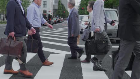 Several-japanese-business-People-crossing-a-street-in-Central-Tokyo,-Japan-on-an-overcast-day