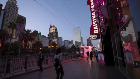 People-Walking-Along-Las-Vegas-Strip-Pavement-Beside-Raising-Cane-Restaurant-In-The-Evening