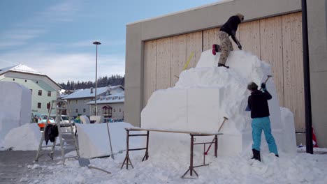 South-Tyrolean-artists-work-on-their-snow-sculpture,-Embryo-2300,-during-the-33rd-Dolomites-Snow-Festival-in-Innichen---San-Candido,-South-Tyrol,-Italy