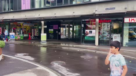 Corner-Road-Along-Urban-Sidewalk-|-Interlaken-Switzerland-Immersive-Travel-Tourism-Mountainside-Valley-Resort-City,-Europe,-Walking,-Rainy-Day,-4K