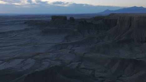 Hombre-De-Paso-Elevado-Aéreo-Parado-En-La-Cresta-Con-Vistas-Al-Misterioso-Paisaje-Lunar-De-Butte-De-Fábrica-Al-Amanecer