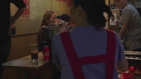 Woman-tourist-drinking-a-drink-at-omoide-yokocho-alley-in-Shinjuku-Tokyo,-Japan