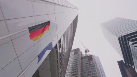 Commerzbank-Tower-Mit-Der-Deutschen-Und-Der-Europäischen-Flagge-Davor-An-Einem-Bewölkten-Tag