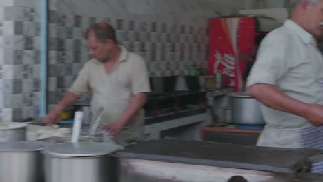 Gente-En-Cámara-Lenta-Haciendo-Comida-Tradicional-India-En-La-Calle-En-Un-Puesto-Del-Mercado-Al-Lado-De-La-Carretera