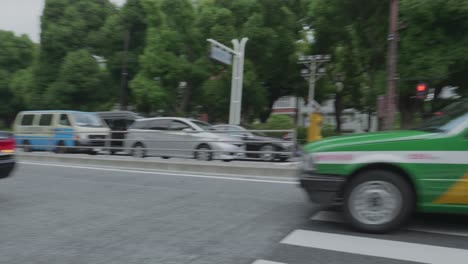 Black-Japanese-Taxi-Cars-Driving-Past-A-Local-Street-In-Tokyo-Japan-On-A-Sunny-Day