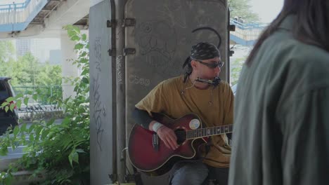 Un-Músico-Callejero-En-Tokio-Tocando-Su-Guitarra-En-Un-Día-Soleado-Mientras-Mucha-Gente-Pasa