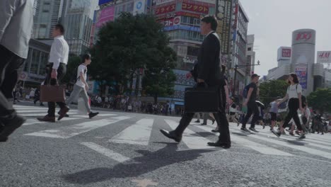 Thousands-of-People-walking-over-the-world-famous-Shibuya-Crossing,-which-is-the-busiest-intersection-in-the-world,-on-a-beautiful-sunny-day-in-slow-motion