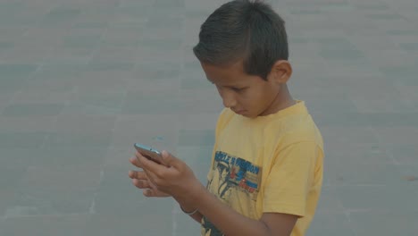 Un-Joven-Indio-Solo-En-La-Calle-Jugando-Con-Un-Teléfono-Móvil