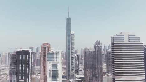 Luftdrohnenaufnahmen-Der-Jumeirah-Lake-Towers-Mit-Dem-Almas-Tower-Vorne-Und-Dem-Dubai-Marina-Im-Hintergrund-An-Einem-Sehr-Sonnigen-Und-Hellen-Tag