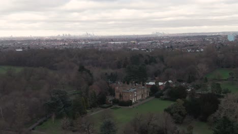 Aerial-drone-shot-of-Addington-Palace-in-Croydon,-London,-United-Kingdom-on-a-cloudy-day-and-with-London-Downtown-Cityscape-in-the-background