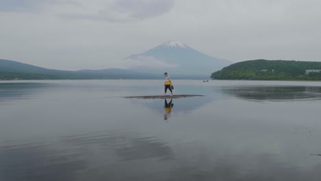 Cámara-Lenta-De-Un-Joven-Caminando-Sobre-El-Banco-De-Arena-Del-Lago-Frente-Al-Monte-Fuji