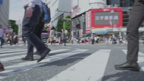 Thousands-of-People-walking-over-the-world-famous-Shibuya-Crossing,-which-is-the-busiest-intersection-in-the-world,-on-a-beautiful-sunny-day-in-slow-motion