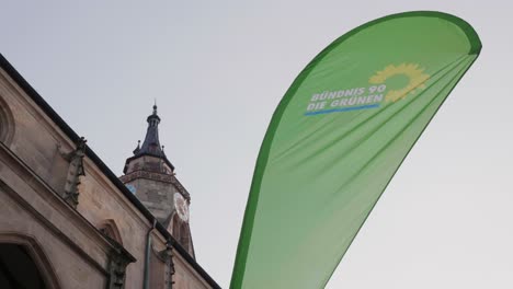 Flag-of-the-political-party-Bündnis-90-Die-Grünen-in-front-of-a-church-in-Tübingen,-Germany