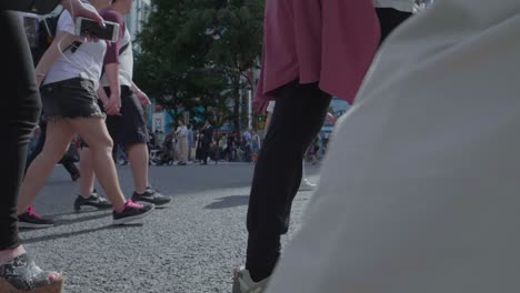 Thousands-of-People-walking-over-the-world-famous-Shibuya-Crossing,-which-is-the-busiest-intersection-in-the-world,-on-a-beautiful-sunny-day-in-slow-motion