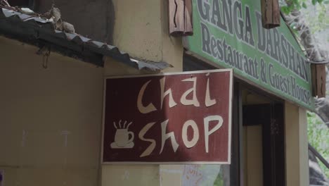 Panorámica-Hacia-Un-Cartel-De-Una-Tienda-En-Una-Acera-Que-Anuncia-Una-Tienda-Chai-En-La-India