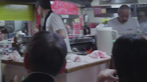 Camera-walking-through-the-famous-Omoide-Yokocho-Alley-in-Tokyo,-Japan-at-night-with-many-people-eating-and-drinking