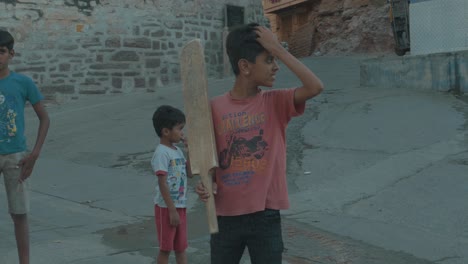 Porträt-Eines-Indischen-Jungen,-Der-Auf-Der-Straße-In-Indien-Mit-Einem-Glücklichen-Gesichtsausdruck-In-Die-Kamera-Lächelt-Und-Cricket-Spielt