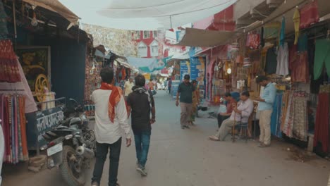 Caminando-Por-Un-Mercado-Indio-Con-Coloridas-Tiendas-Llenas-De-Artículos-Para-Comprar-Ocupado-Con-Gente-Local