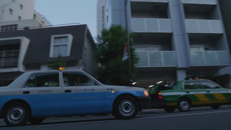 Cars-and-cabs-driving-through-the-streets-of-Tokyo,-Japan-in-the-early-evening