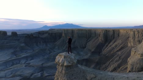 Lone-Drone-Operator-Standing-On-Desert-Stone-Column-Flying-Drone-During-Sunset-At-Moonscape-Overlook-In-Utah