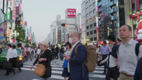 Many-japanese-people-cross-a-packed-road-in-Shinjuku,-Tokyo-while-rush-hour