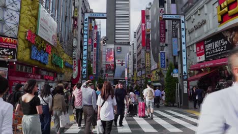 Many-japanese-people-cross-a-packed-road-in-Shinjuku,-Tokyo-while-rush-hour