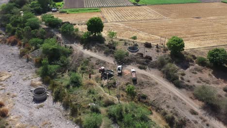 Vista-Aérea-De-Drones-Los-Hombres-Con-Cámara-De-Drones-Están-Llenando-El-Tractor-Con-Polvo-Y-Saliendo