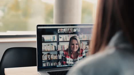 Kaukasische-Frauen,-Die-An-Einem-Hellen-Tag-Mit-Ihrem-Notebook-In-Einem-Modernen-Büroraum-An-Einer-Videokonferenz-Teilnehmen-Und-Dabei-Aus-Nächster-Nähe-über-Die-Schulter-Schauen