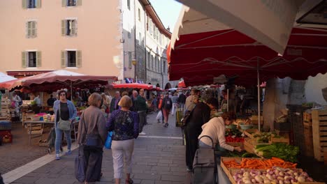 En-El-Corazón-Del-Casco-Antiguo,-La-Gente-Recorre-Los-Puestos-Del-Mercado-Del-Casco-Antiguo-De-Annecy.