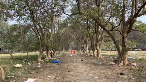 Wide-angle-view-of-saddhus-approaching-towards-from-a-pathway-in-a-forest-of-Kolkata,-India-during-daytime