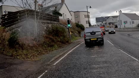 Traffic-waiting-at-a-green-light-on-a-cloudy-day-in-Kyle-of-Lochalsh,-Scotland,-with-hints-of-nature