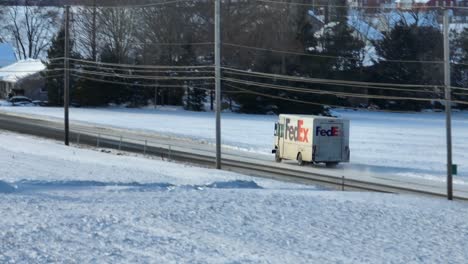 Camión-De-Reparto-De-Fedex-Conduciendo-Por-Una-Carretera-Cubierta-De-Nieve-En-Las-Zonas-Rurales-De-EE.UU.-En-Invierno