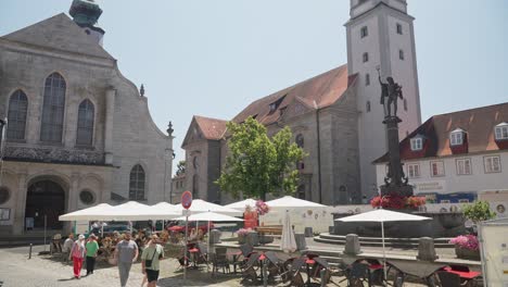 Día-Soleado-En-Una-Cafetería-Lindau-Con-Lugareños-Disfrutando-Del-Clima-Cerca-De-Edificios-Históricos-Y-Una-Estatua