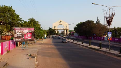 Very-slow-descending-aerial-shot-of-traffic-at-arch-22-Banjul-entrance-highway,-Gambia---West-Africa