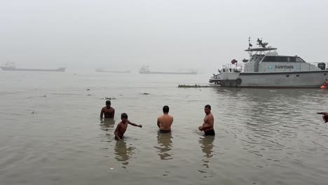 Rückansicht-Einiger-Männer-Und-Jungen,-Die-An-Einem-Bewölkten-Abend-In-Babu-Ghat,-Kalkutta,-Baden-Und-Beten