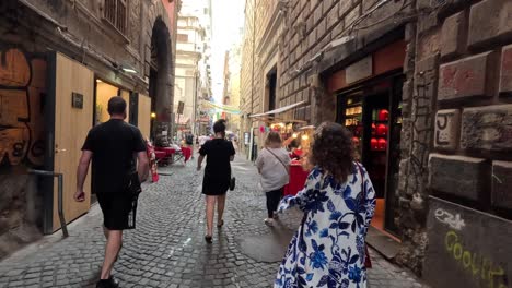 Tourists-walk-in-the-narrow-street-with-graphite-and-small-shops-in-the-city-centre-of-Naples-in-Italy