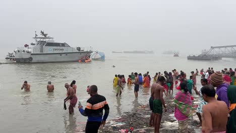 Vista-Trasera-De-Personas-Bañándose-Y-Rezando-Durante-Sankranti-Cerca-De-Un-Embarcadero-En-Babughat,-Kolkata-Durante-La-Puesta-De-Sol